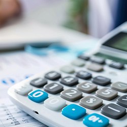 Large model tooth on top of an invoice next to a calculator and a hand on a laptop