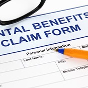 Top of blue and white “Dental Benefits Claim Form” with blue pen and black glasses