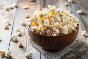 Bowl of popcorn overflowing onto a wooden floor